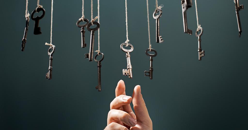 12 keys hanging on thread while a hand reaches above in the center