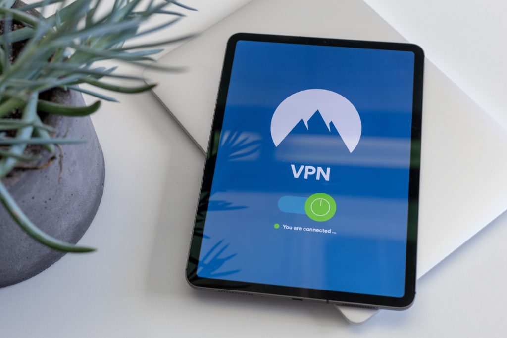 Tablet displaying the words vpn connected, sitting on a laptop computer with a plant to the left